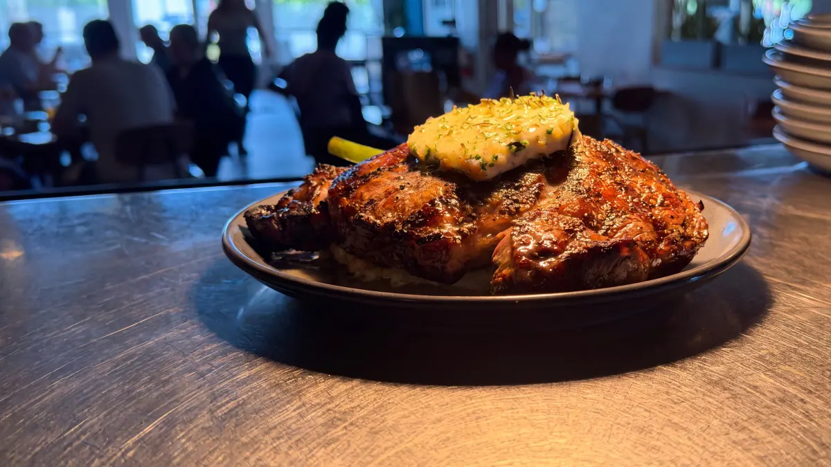 A bone-in steak under melting herb butter in the Charred dining room