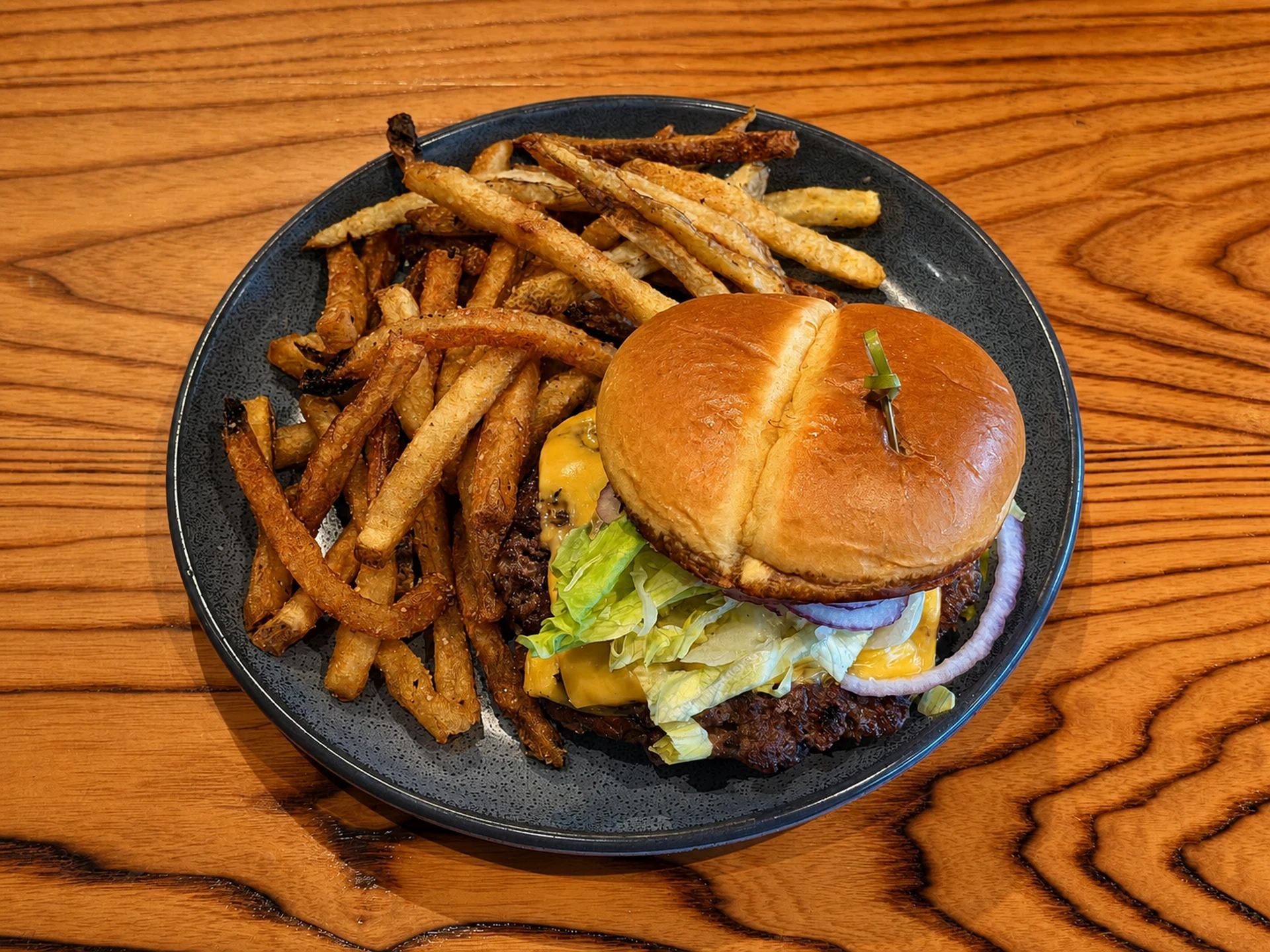 A smash burger with hand-cut fries on a dark plate