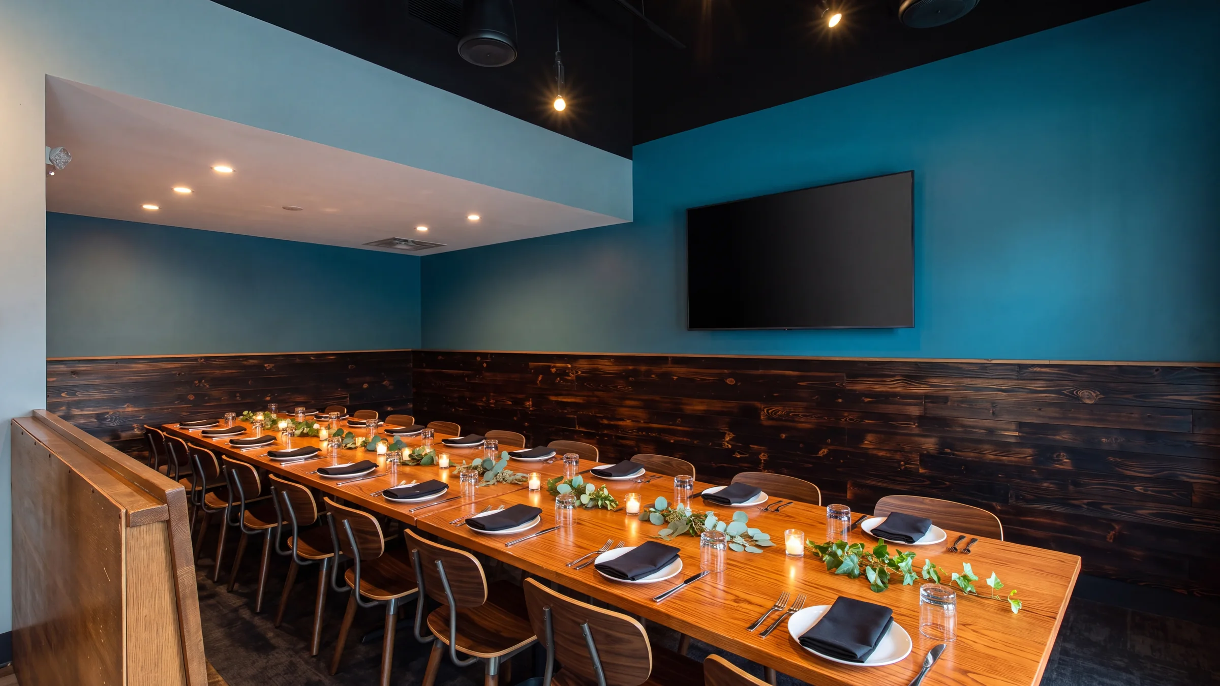 The teal and charred-wood private dining room set with a long table for a group dinner