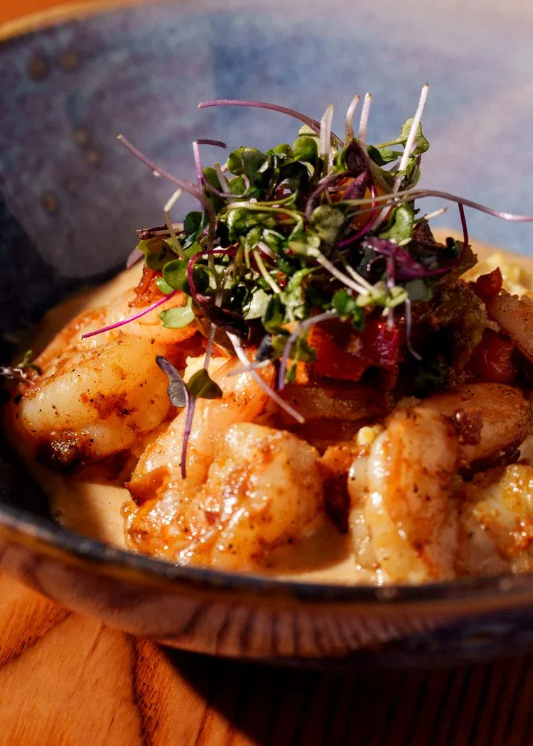 Cajun shrimp and grits finished with bacon and microgreens