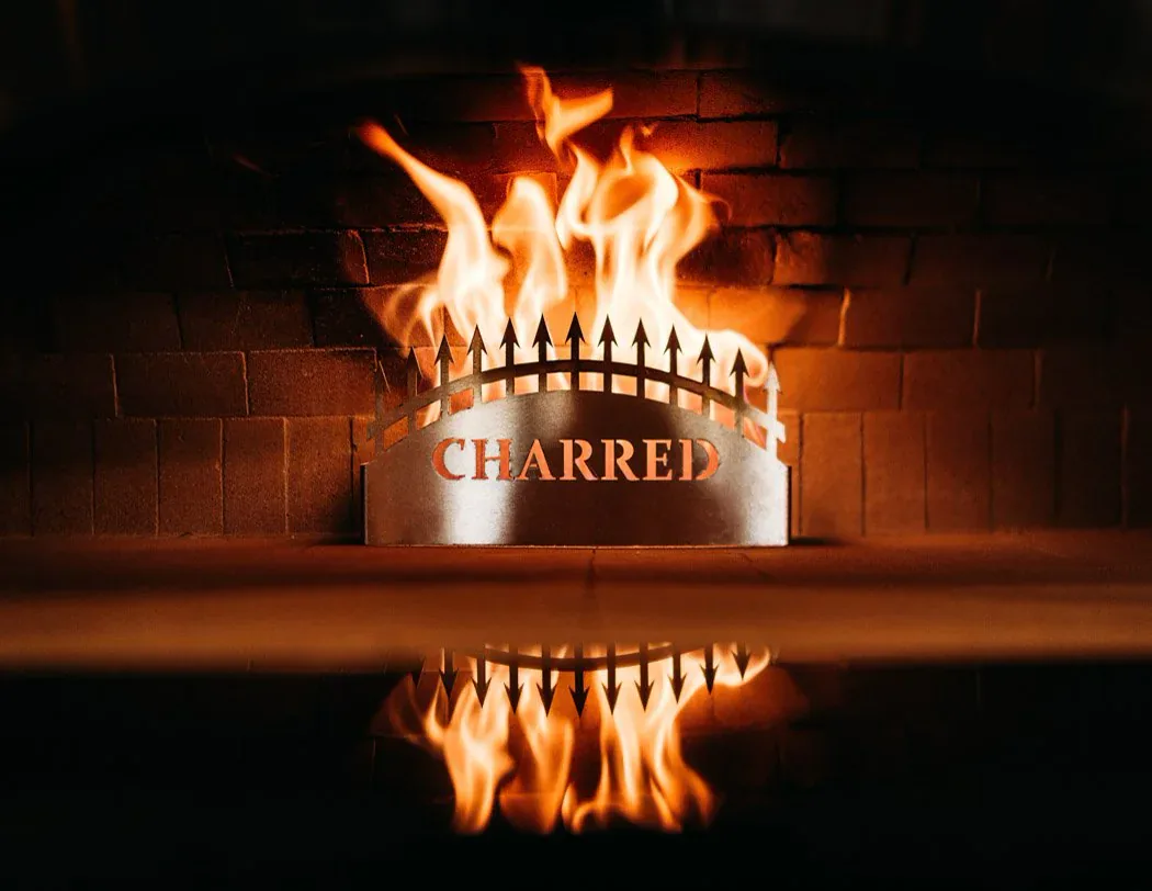 The Charred fire ring glowing in front of the brick oven