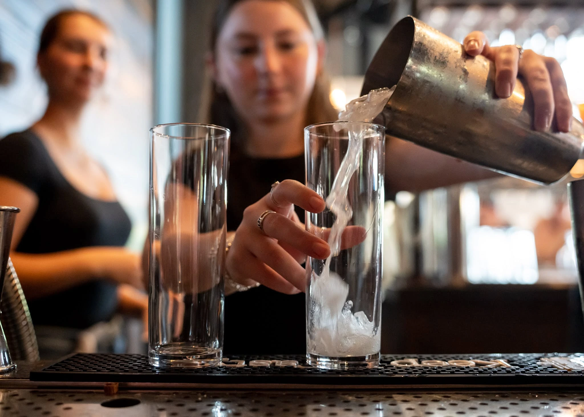 A Charred bartender pouring a drink behind the bar