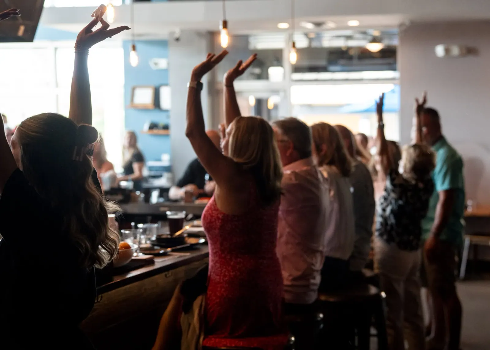 Guests raising their hands together during a community celebration at Charred