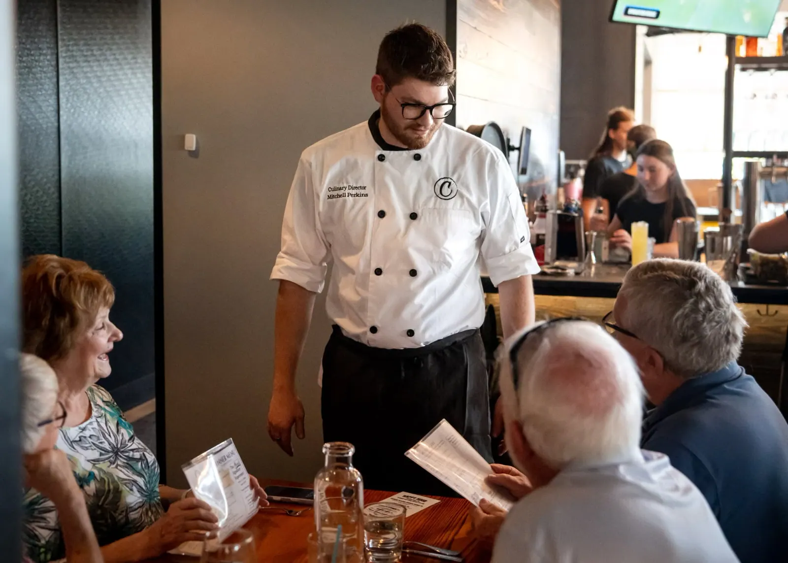 Charred Culinary Director Michael Perkins talking through the menu with guests at their table