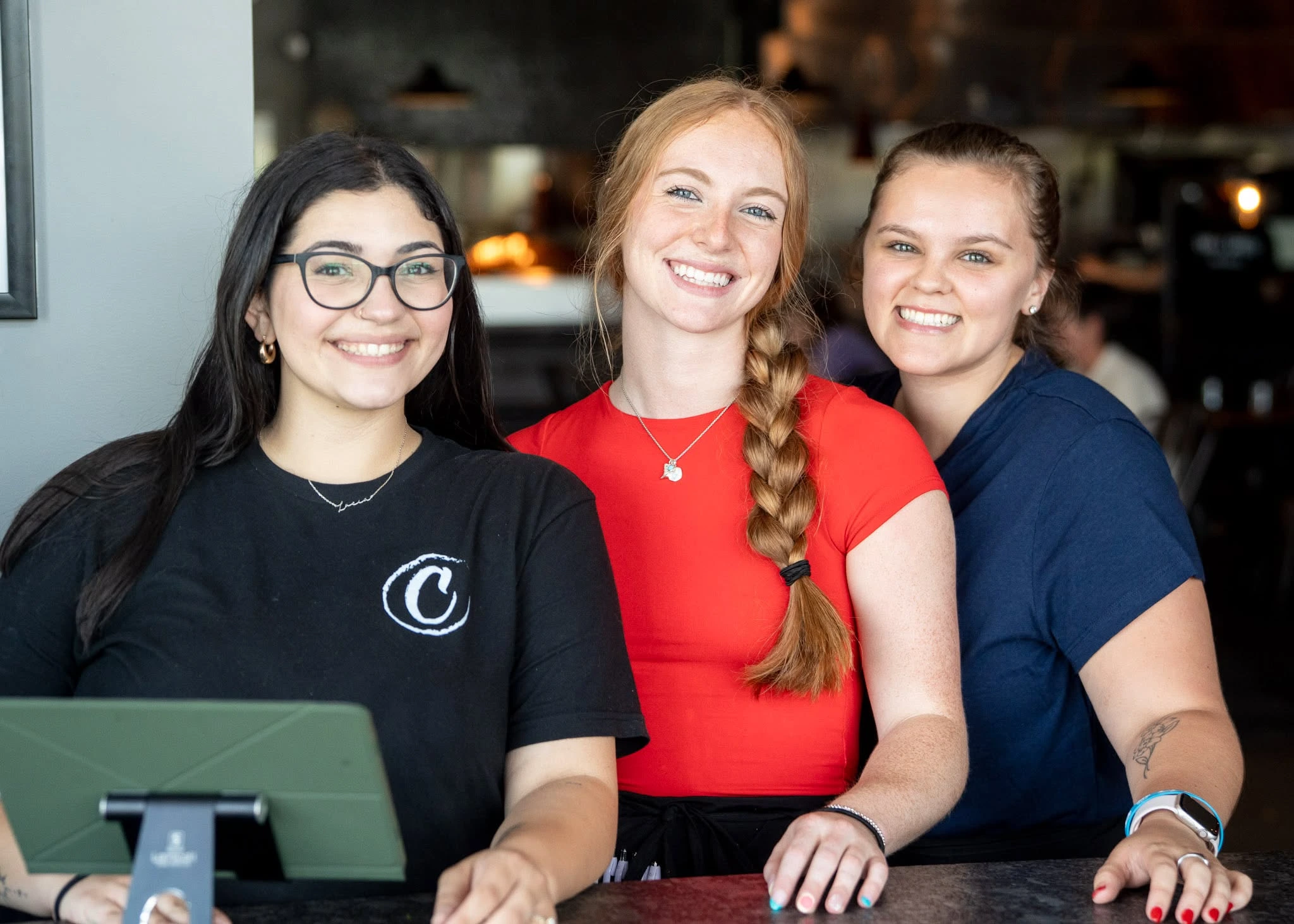 Three members of the Charred front-of-house team behind the host stand