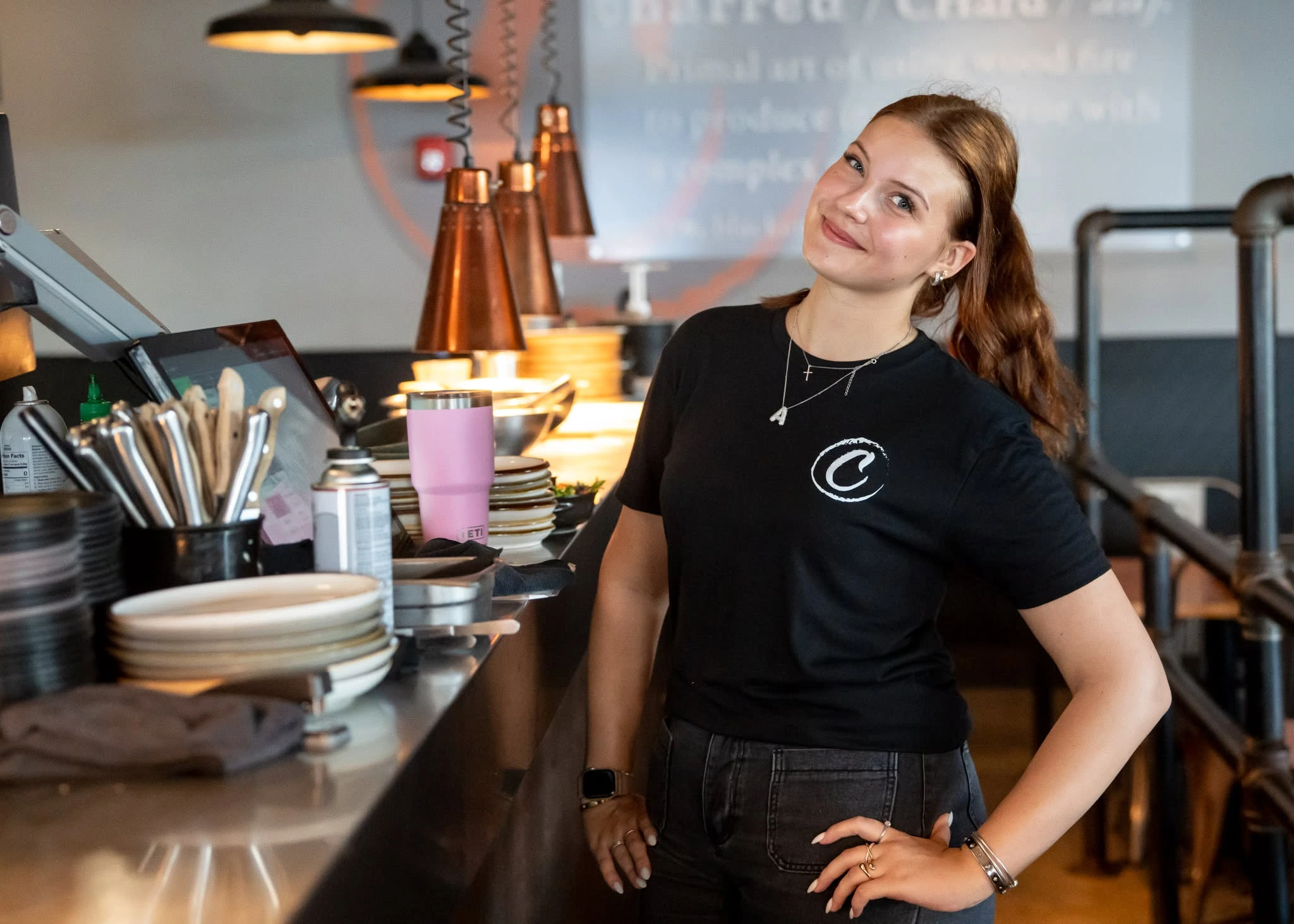 A Charred server smiling at the kitchen pass